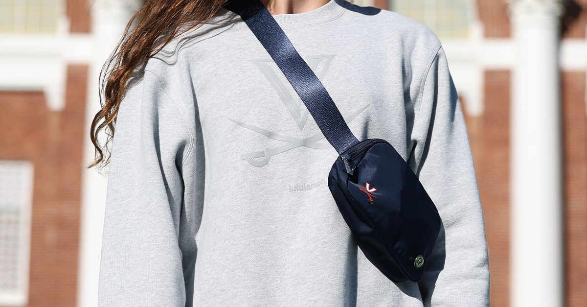 From the lululemon meets UVA collection a close up of the cross body bag over a light gray sweatshirt.